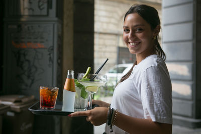 Portrait of a smiling young woman holding drink