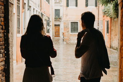 Rear view of two women standing on street in city