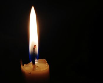 Close-up of lit candle in darkroom