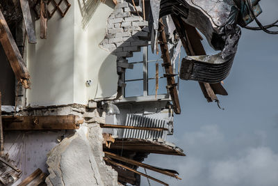 Low angle view of machinery demolishing building against sky