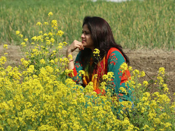 Young woman with yellow flowers on field