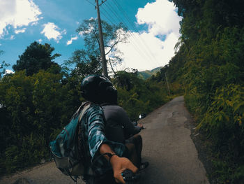 Rear view of man riding motorcycle on road against sky