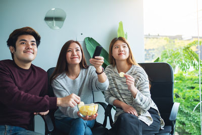 Friends eating potato chips while watching tv together