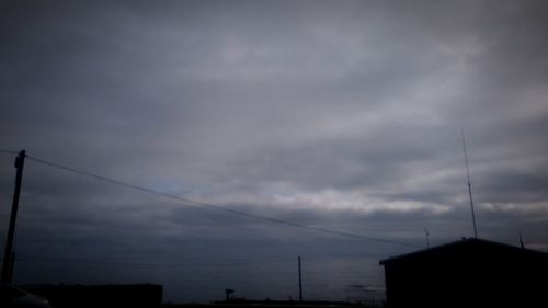 Low angle view of power lines against cloudy sky