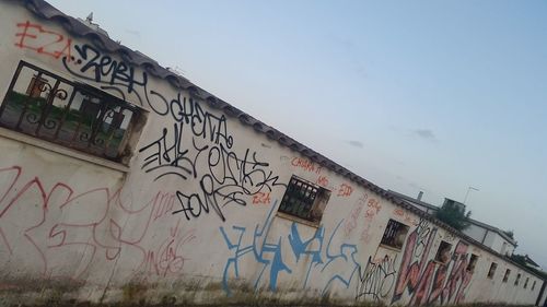 Low angle view of graffiti on city against sky