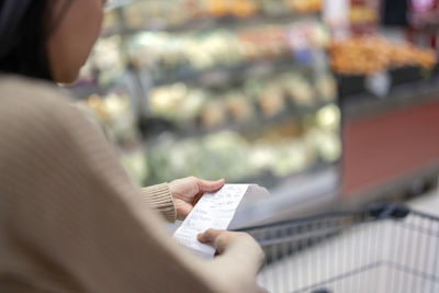 Woman examining shopping list at supermarket