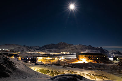 Scenic view of illuminated snowcapped mountains against sky at night