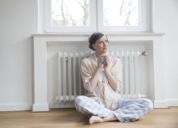 Woman at home sitting on floor holding cup