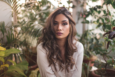 Portrait of beautiful young woman standing against plants