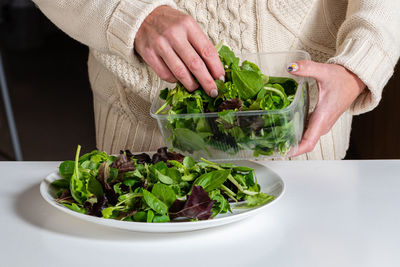 Middle aged blonde woman preparing green salad in the kitchen, healthy eating and diet concept,