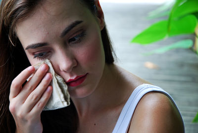 Close-up of young woman wiping make-up from face outdoors