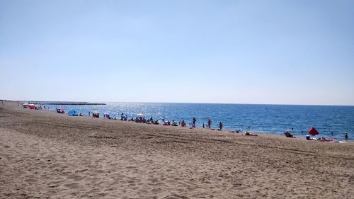 Group of people on beach against clear sky