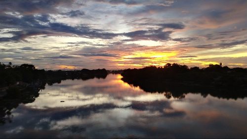 Scenic view of lake against dramatic sky during sunset