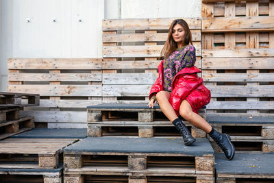 Fashionable smiling young woman sitting on palettes