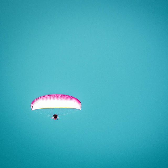 low angle view, flying, mid-air, clear sky, copy space, blue, parachute, hot air balloon, multi colored, adventure, no people, outdoors, fun, freedom, pattern, sky, day, balloon, hanging, red