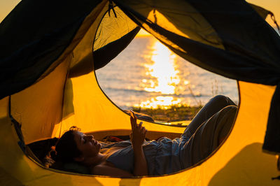 Rear view of woman lying on orange during sunset