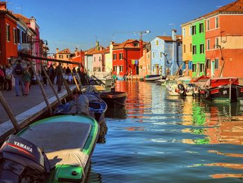 Boats moored in canal amidst buildings in city