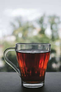 A cup of black tea standing by the window on the background of the street