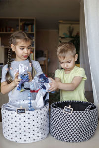 Cute sibling putting clothes in container