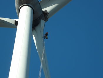 Low angle view of wind turbine against blue sky