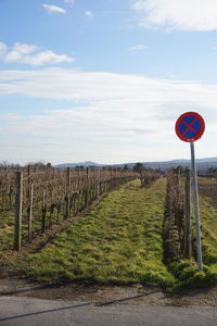 Road sign on field against sky