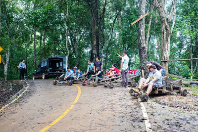 People sitting on road amidst trees in forest