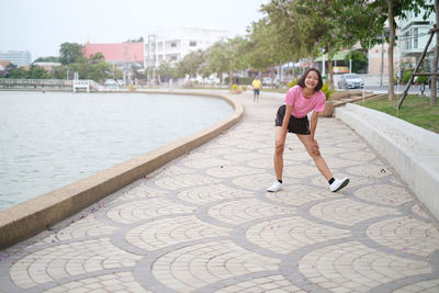 Full length smiling teenage girl standing on footpath