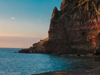 Rock formations by sea against sky