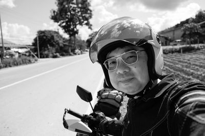 Portrait of mature man wearing helmet with motorcycle on road