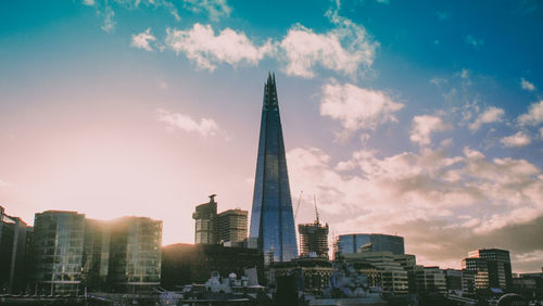 Modern buildings in city against sky during sunset