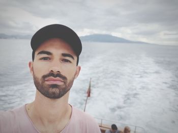 Portrait of young man in boat at sea against sky