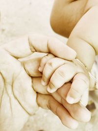 Midsection of father holding baby hand