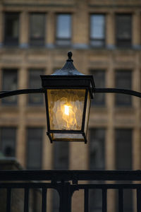 Close-up of illuminated lamp post against building