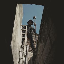 Portrait of smiling man standing on wall against clear sky