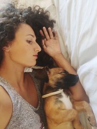 Midsection of woman sleeping with her dog on bed