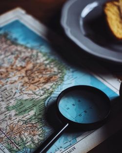 Close-up of magnifying glass on map at table