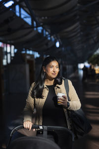 View of woman holding disposable cup at train station