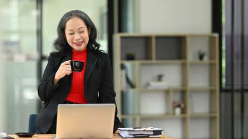 Young woman using laptop while sitting on table