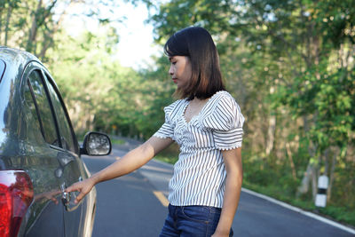 Side view of woman standing in car