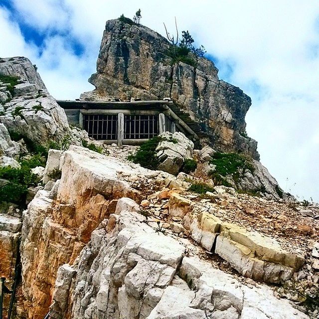 architecture, building exterior, built structure, sky, low angle view, history, famous place, mountain, travel destinations, the past, ancient, old, cloud - sky, old ruin, tourism, travel, religion, cloud, rock - object, place of worship