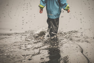 Low section of man standing on wet beach