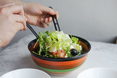 Cropped image of hand holding bowl of food