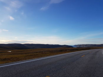 Empty road by mountains against sky