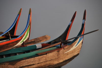 Close-up of boats moored on beach against sky