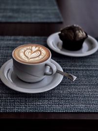 Close-up of coffee in cup with cupcake on table