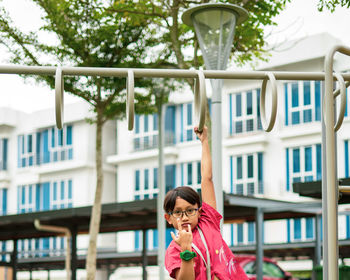 Young asian children hang on the monkey bar. to exercise at outdoor playground in the neighbourhood.