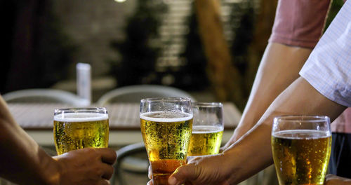 Cropped hands of friends toasting beer glasses