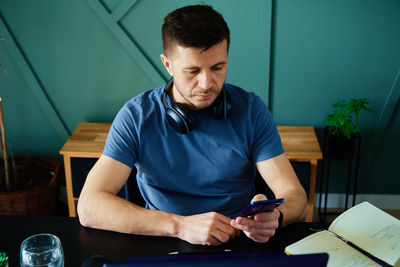 Bored man playing smartphone while working at home office