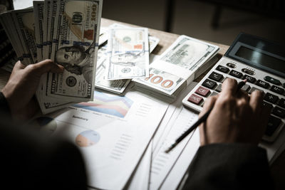 Midsection of businessman using calculator on table