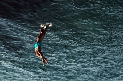 Upside down image of shirtless man diving into sea